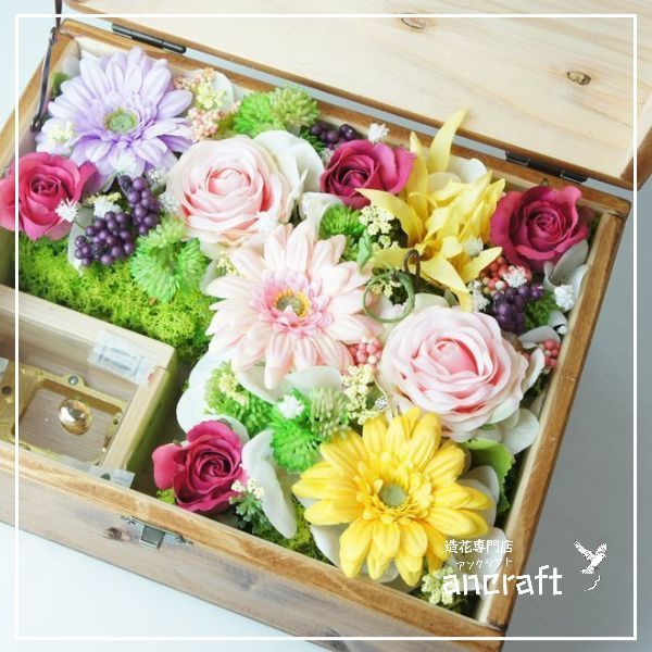 オルゴールBOXアレンジ　高級造花専門店アンクラフトは１級フラワー装飾技能士がアーティフィシャルフラワー（造花）を使用し、ご希望のアレンジメント、髪飾り、ブーケをオーダーメイドで制作致します。結婚記念日やお見舞いの花、花言葉に合わせたお花の贈り物や開店花、待合室用、応接用花、個性的な髪飾りや派手な花、大人可愛い、おしゃれなバラなどどんなオーダーでもお気軽にお問い合わせください。大阪、兵庫県、関西からアクセスが簡単。
