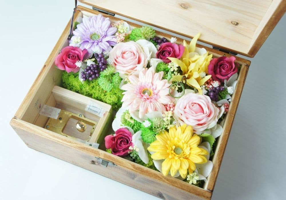 オルゴールBOXアレンジ　高級造花専門店アンクラフトは１級フラワー装飾技能士がアーティフィシャルフラワー（造花）を使用し、ご希望のアレンジメント、髪飾り、ブーケをオーダーメイドで制作致します。結婚記念日やお見舞いの花、花言葉に合わせたお花の贈り物や開店花、待合室用、応接用花、個性的な髪飾りや派手な花、大人可愛い、おしゃれなバラなどどんなオーダーでもお気軽にお問い合わせください。大阪、兵庫県、関西からアクセスが簡単。