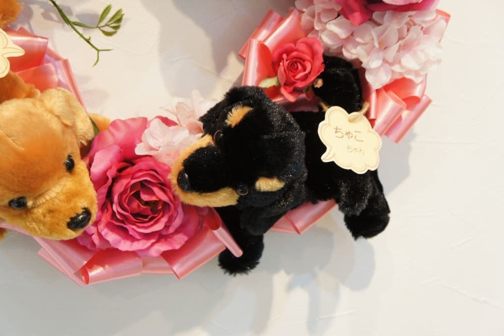 わんこのリース　高級造花専門店アンクラフトは１級フラワー装飾技能士がアーティフィシャルフラワー（造花）を使用し、ご希望のアレンジメント、髪飾り、ブーケをオーダーメイドで制作致します。結婚記念日やお見舞いの花、花言葉に合わせたお花の贈り物や開店花、待合室用、応接用花、個性的な髪飾りや派手な花、大人可愛い、おしゃれなバラなどどんなオーダーでもお気軽にお問い合わせください。大阪、兵庫県、関西からアクセスが簡単。